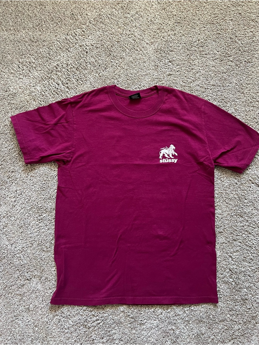 Stussy Short-Sleeve T-Shirt in Magenta with White Lion Graphic.